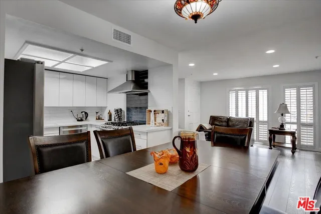 a kitchen with stainless steel appliances granite countertop a stove refrigerator a couch and a dining table with wooden floor