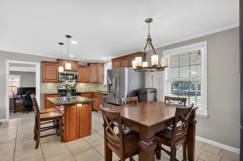 a kitchen with stainless steel appliances a dining table chairs a refrigerator and microwave