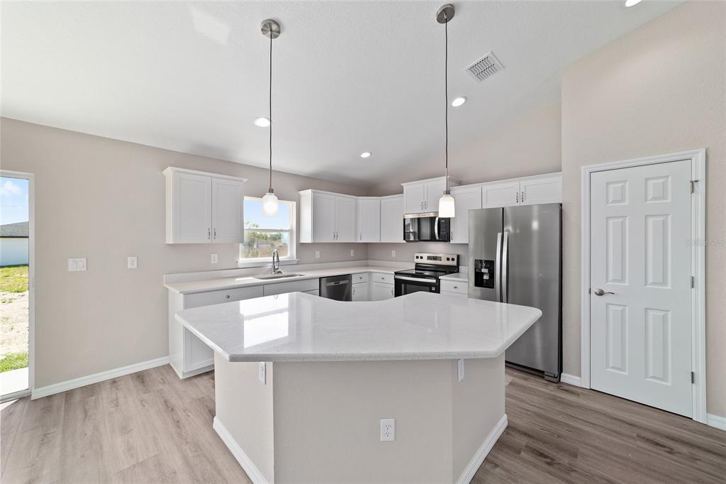19330 Southwest 91st Loop Dunnellon, FL 34432 - Photo 24 of 46 a kitchen with kitchen island a sink a center island a stove and a wooden floor