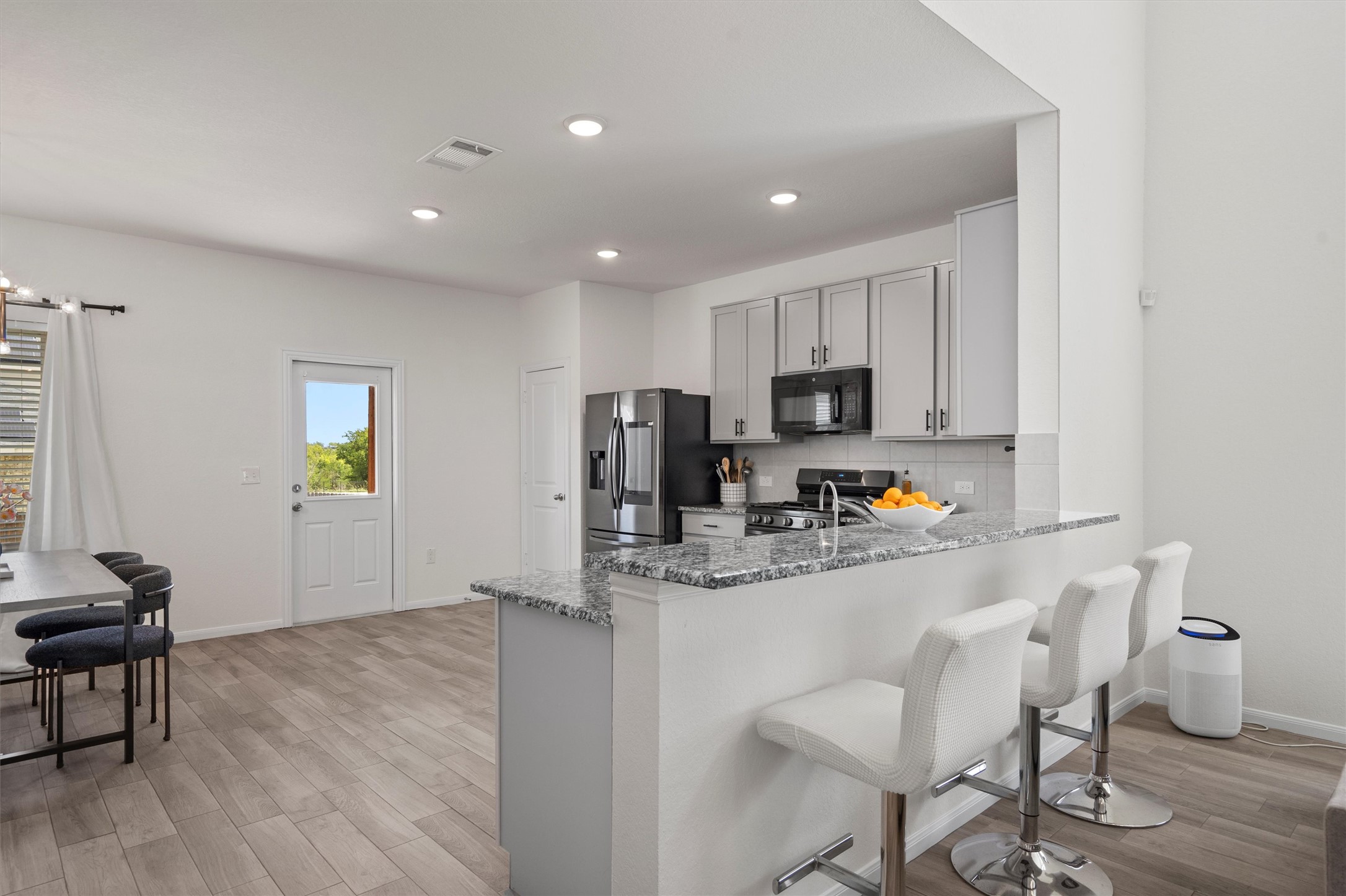 6720 Coalinga Lane Pflugerville, TX 78660 - Photo 12 of 38 a kitchen with stainless steel appliances granite countertop a stove a sink a refrigerator white cabinets and wooden floor