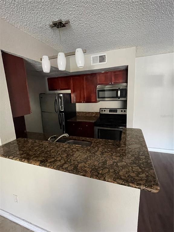 5148 Conroy Road, Unit 1214 Orlando, FL 32811 - Photo 4 of 16 a kitchen with wooden cabinets and a counter top space