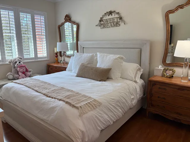 a bedroom with a bed large window and potted plant on table