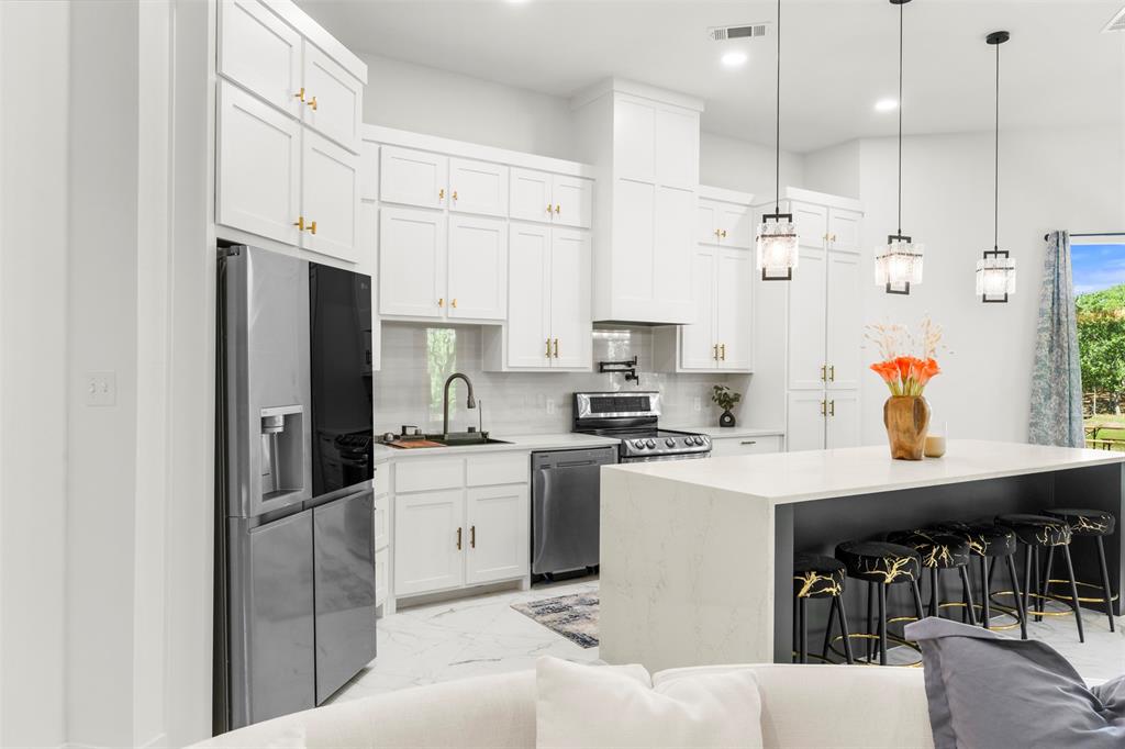 265 Shadow Oaks Streetman, TX 75859 - Photo 8 of 40 a kitchen with stainless steel appliances kitchen island granite countertop a refrigerator a sink a stove and white cabinets