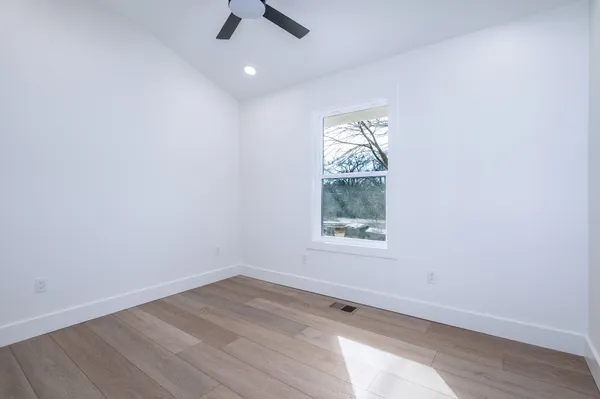 an empty room with a window and a ceiling fan