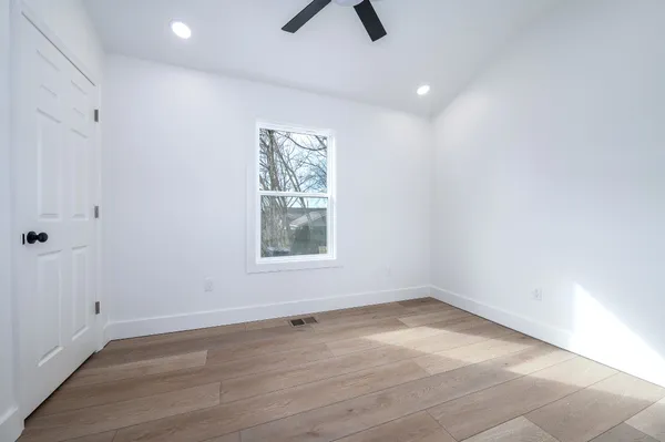 an empty room with ceiling fan and window