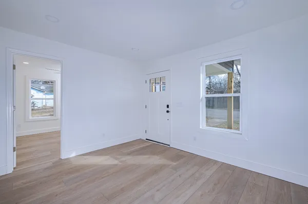 an empty room with wooden floor and windows