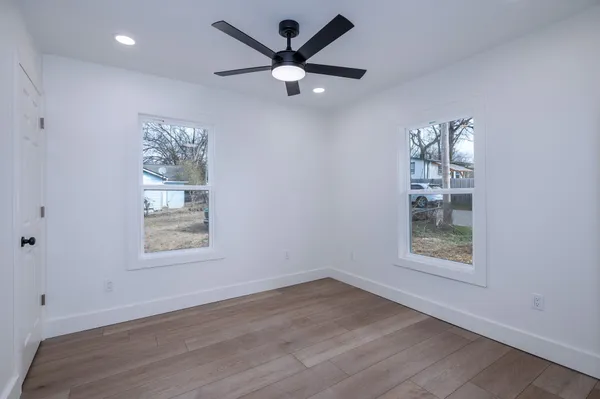 an empty room with wooden floor and windows