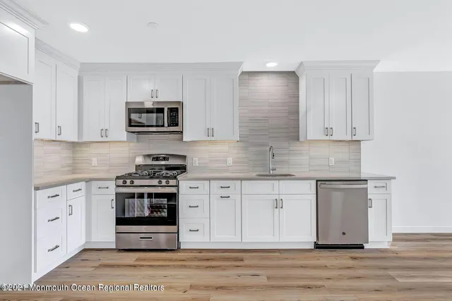 a kitchen with stainless steel appliances granite countertop a stove a sink and a microwave