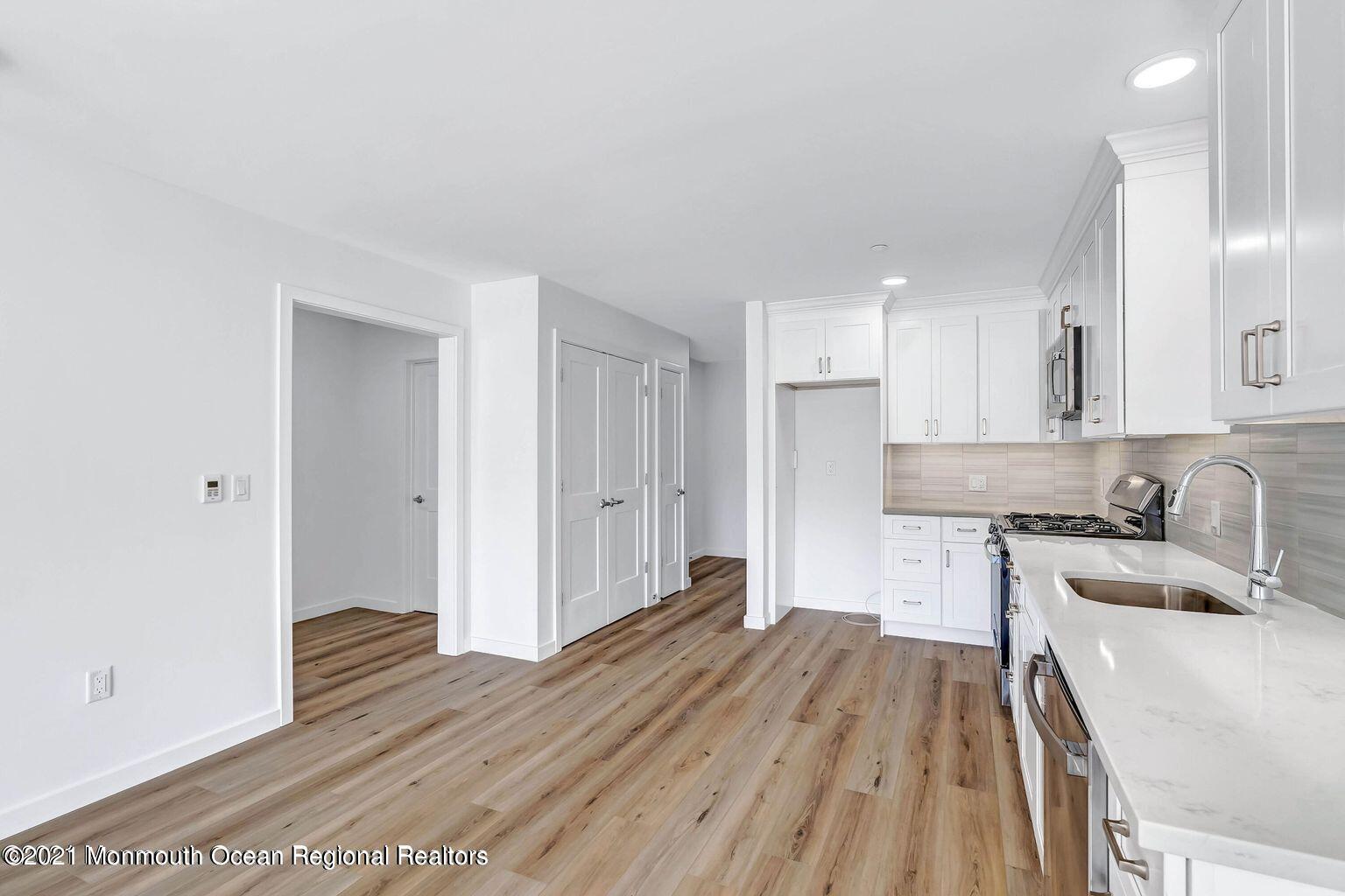 131 Brighton Avenue, Unit 301 Long Branch, NJ 07740 - Photo 8 of 31 a kitchen with wooden floors and white cabinets
