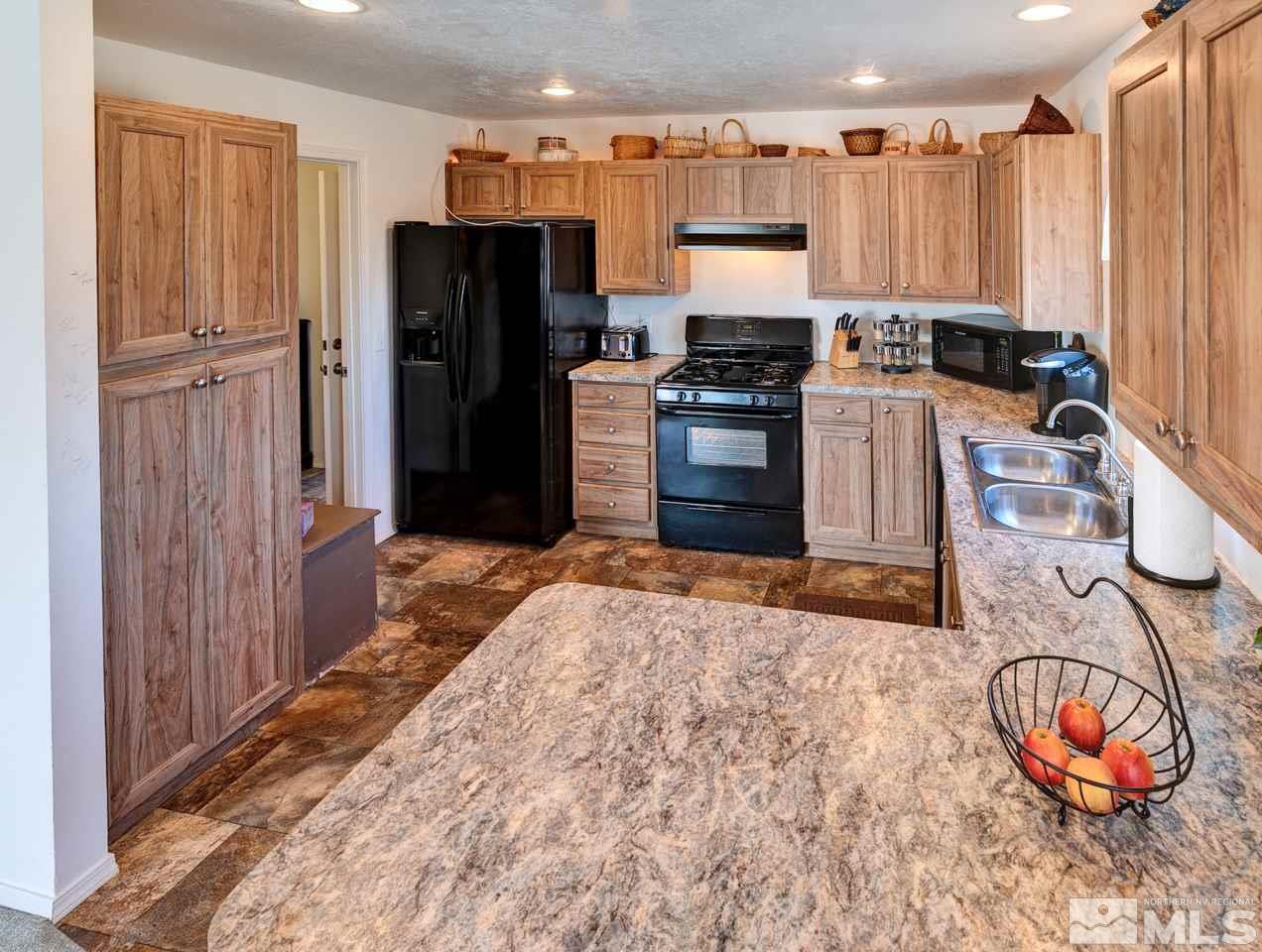 5954 Workman Road Fallon, NV 89406 - Photo 5 of 21 a kitchen with stainless steel appliances granite countertop a refrigerator a stove and a sink with wooden cabinets