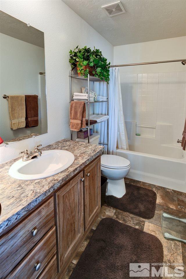 5954 Workman Road Fallon, NV 89406 - Photo 10 of 21 a bathroom with a granite countertop sink a toilet a mirror and shower