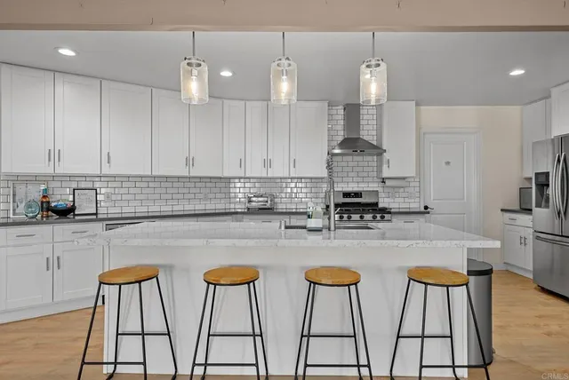 a kitchen with stainless steel appliances granite countertop a stove a sink and white cabinets
