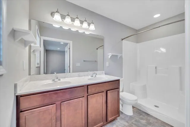 a bathroom with a sink a toilet a large mirror and shower