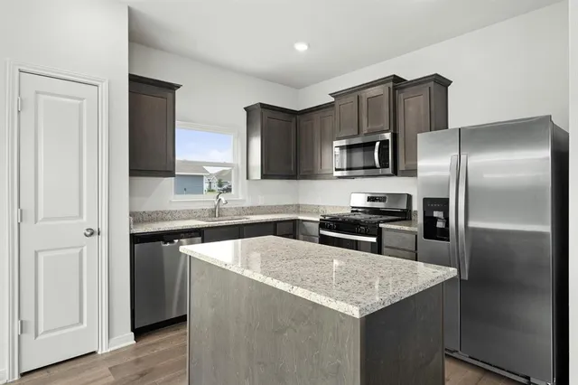 a kitchen with stainless steel appliances granite countertop a refrigerator a stove a sink a microwave and wooden floor