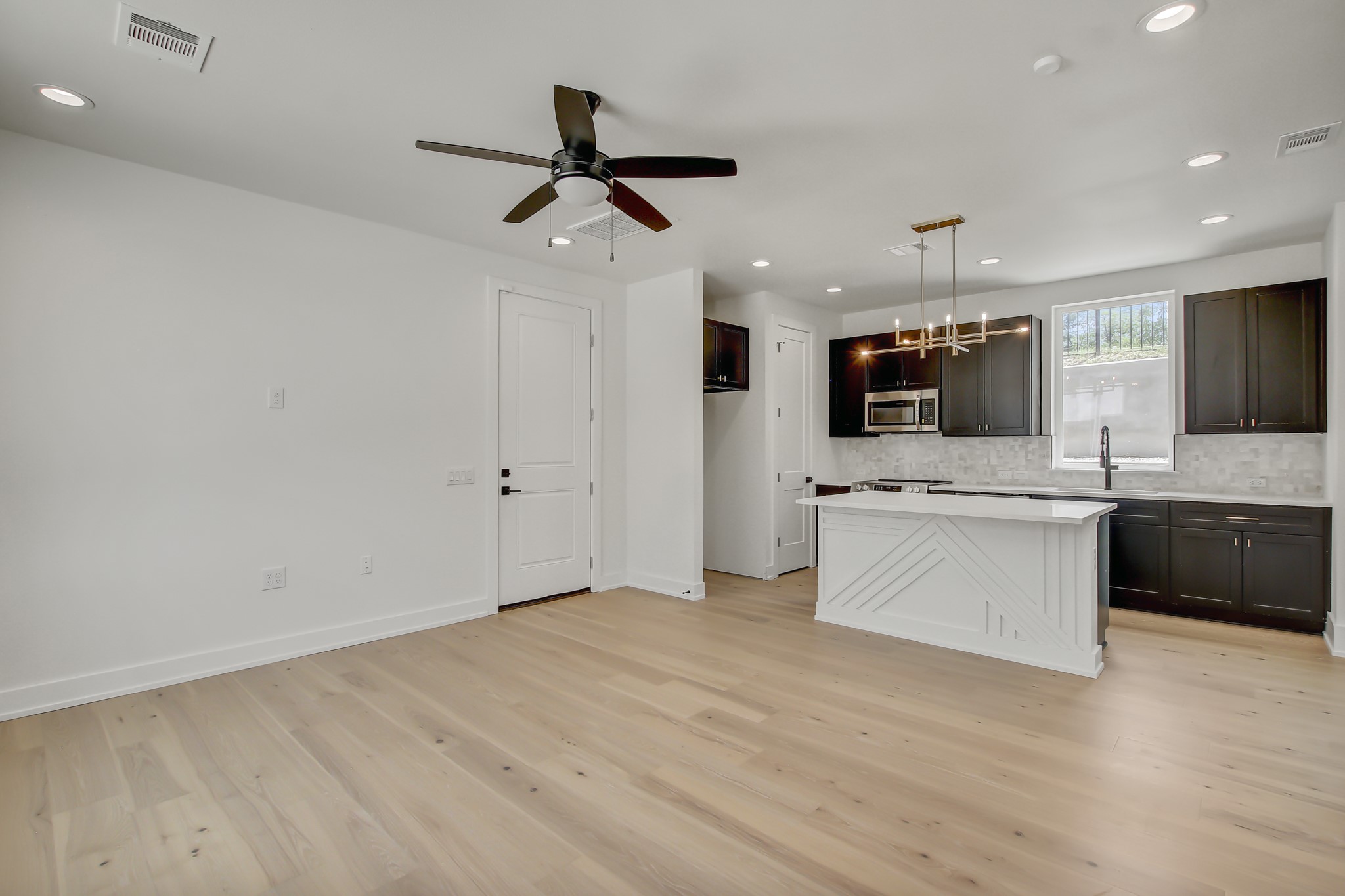 4127 East 12th Street, Unit 8 Austin, TX 78721 - Photo 7 of 32 Kitchen featuring stainless steel microwave, decorative backsplash, light wood-style flooring, recessed lighting, and light countertops