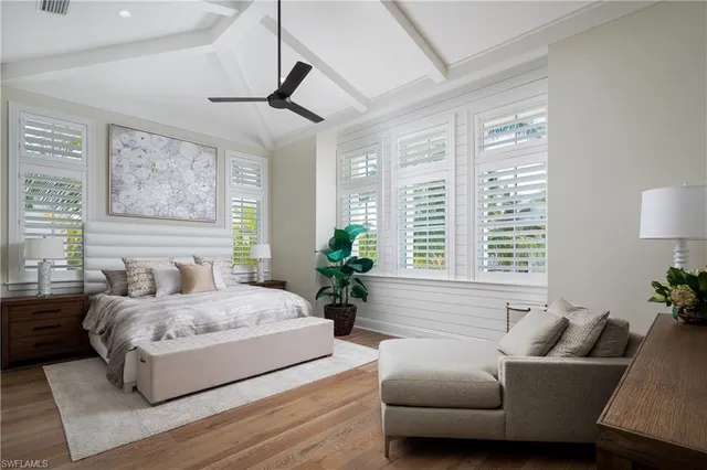 a bedroom with a large bed couch and windows