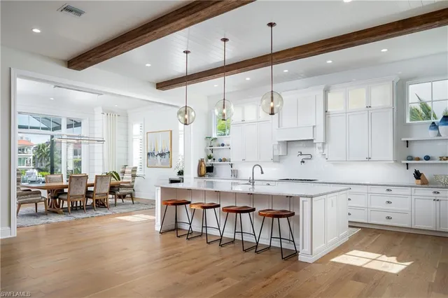 a large white kitchen with lots of counter space wooden floor and appliances
