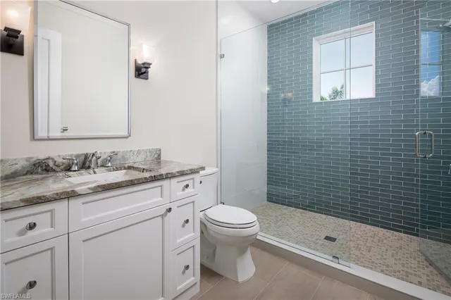 a bathroom with a granite countertop sink a toilet and shower