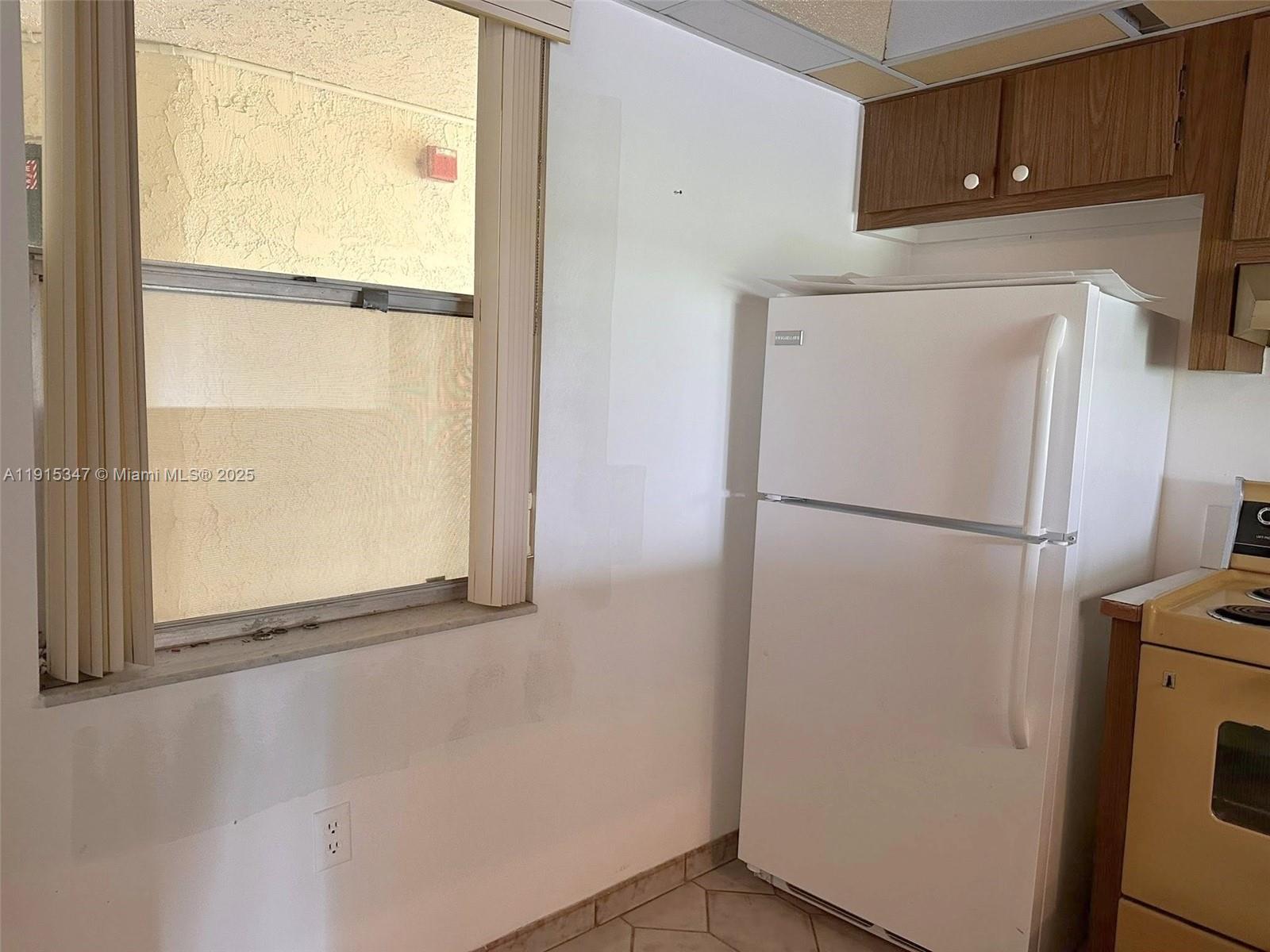 9090 Lime Bay Boulevard, Unit 106 Tamarac, FL 33321 - Photo 17 of 37 a view of a refrigerator in kitchen and an empty room
