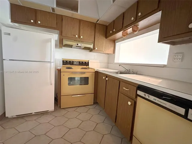 a kitchen with a sink cabinets stainless steel appliances and a window