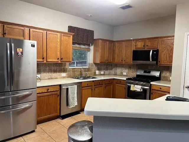 a kitchen with stainless steel appliances granite countertop a refrigerator stove microwave and sink