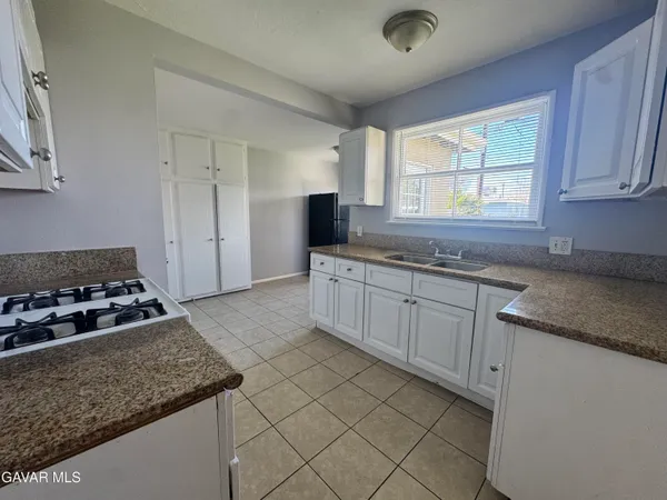 a kitchen with granite countertop a sink a stove and cabinets
