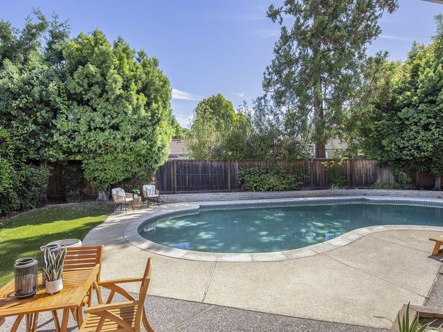 a view of a swimming pool with a sitting space and a small yard