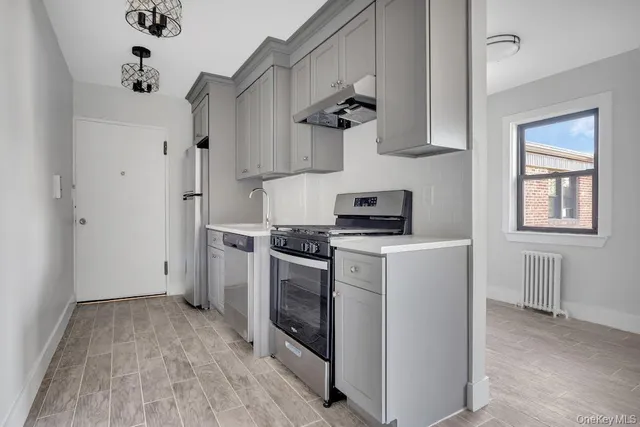 a kitchen with stainless steel appliances a stove a refrigerator and a white cabinets