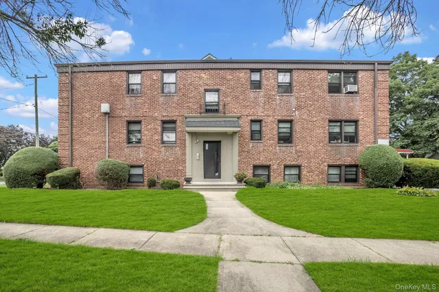 a view of a brick building next to a yard with big trees