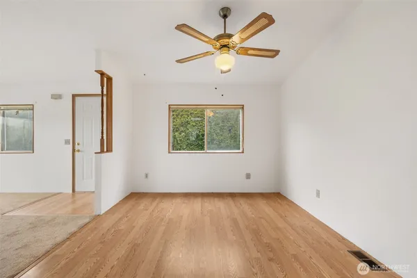 an empty room with wooden floor and windows