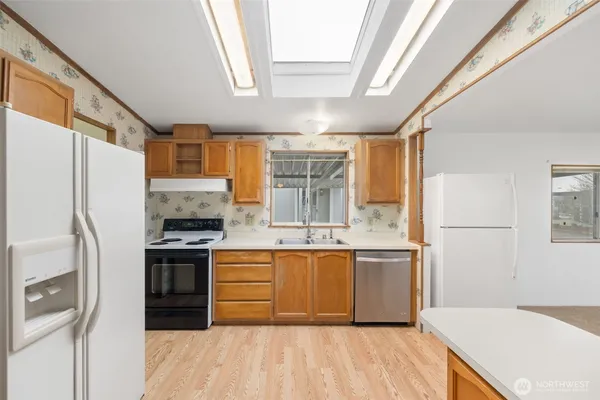 a large kitchen with stainless steel appliances granite countertop a stove a sink dishwasher and a refrigerator