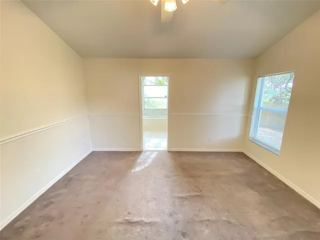 an empty room with chandelier fan and windows