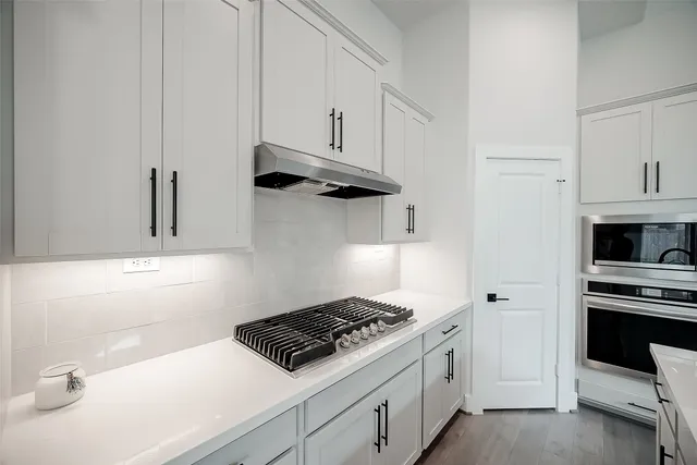 a kitchen with white cabinets and stainless steel appliances