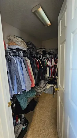 a view of walk in closet with clothes and shoes