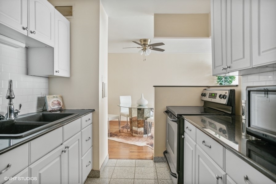 6171 North Sheridan Road, Unit 1204 Chicago, IL 60660 - Photo 7 of 15 a kitchen with a sink dishwasher a stove and a refrigerator with wooden cabinets