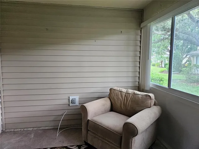 an empty room with a chandelier fan and windows