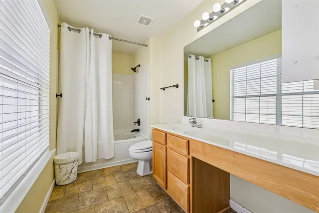 a spacious bathroom with a granite countertop sink toilet and shower