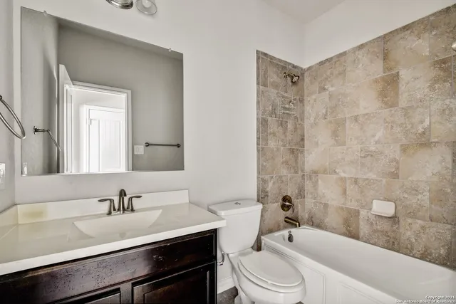 a bathroom with a sink a toilet a mirror a bathtub and shower