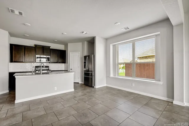 a kitchen with stainless steel appliances granite countertop a stove top oven a sink and a refrigerator