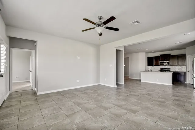 a view of an empty room with kitchen and a window