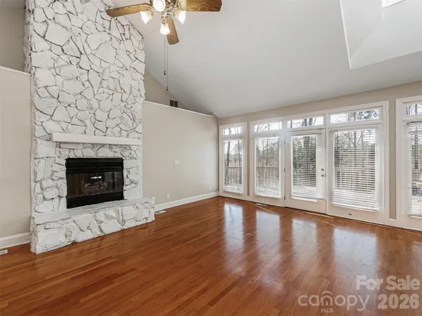 a view of an empty room with wooden floor and a fireplace
