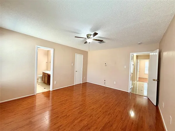 an empty room with wooden floor and a ceiling fan