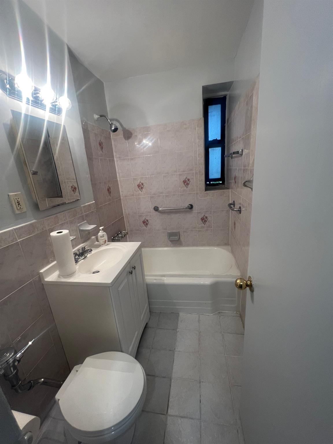 285 East 35th Street, Unit 2D Brooklyn, NY 11203 - Photo 11 of 21 Bathroom with tile walls, vanity, tub / shower combination, and tile patterned floors