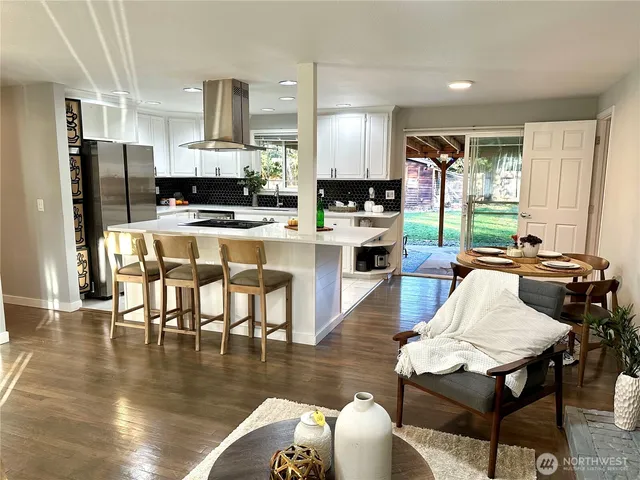 a kitchen with stainless steel appliances a dining table chairs refrigerator and sink