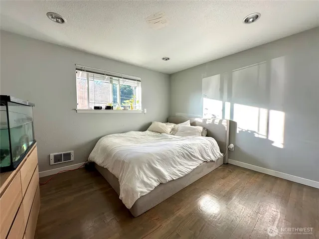 a bedroom with a bed tv and wooden floor