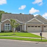 a front view of a house with a garden and trees