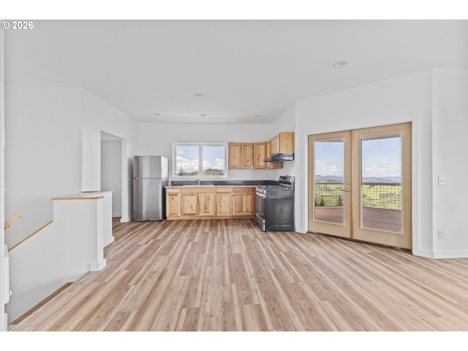 46345 Dement Creek Road Broadbent, OR 97414 - Photo 14 of 47 a large white kitchen with kitchen island a large window a sink and stainless steel appliances