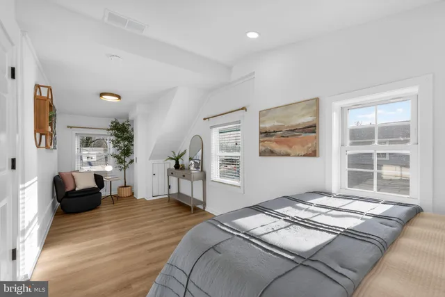 a bedroom with a bed couch and view of living room