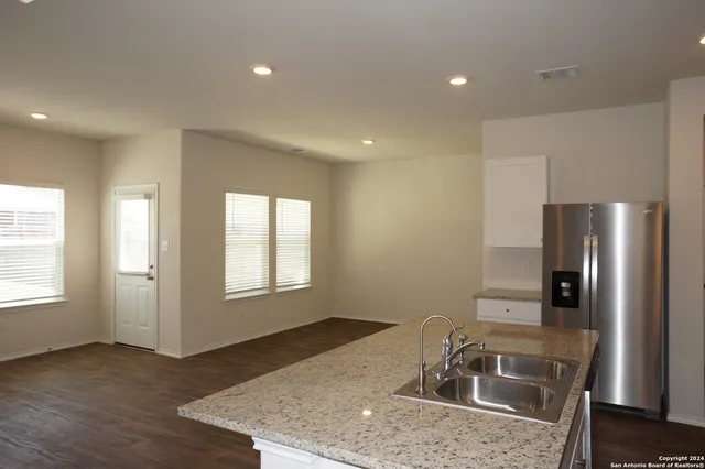a kitchen with stainless steel appliances granite countertop a sink a refrigerator and a granite counter tops