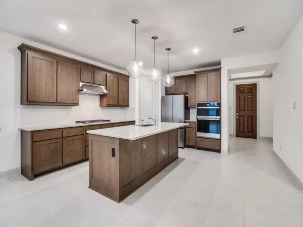 a large kitchen with stainless steel appliances granite countertop a stove a sink a refrigerator and a wooden cabinets